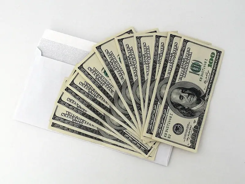 Fan of 100 USA dollar bills on top of an envelope