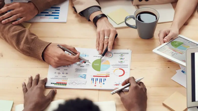 people sat around a table discussing graphs and charts and alternative finance