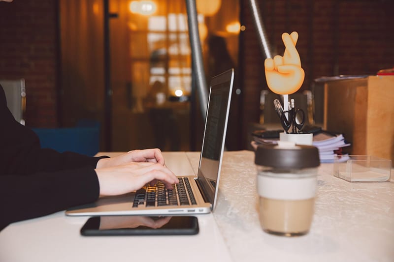 A person wearing black long sleeves working on her laptop