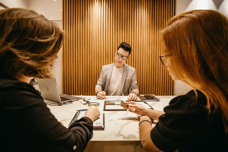 An interviewer writing a note while in front of two applicant