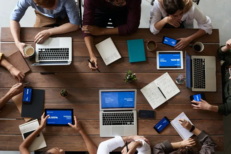 top view photo of people sat around a table with all of their digital devices