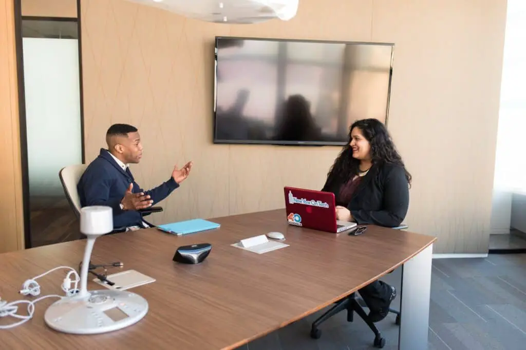 A man in blue suit having a job interview in meeting room with woman in black suit