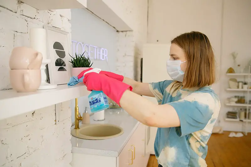 A woman wearing facemask while cleaning