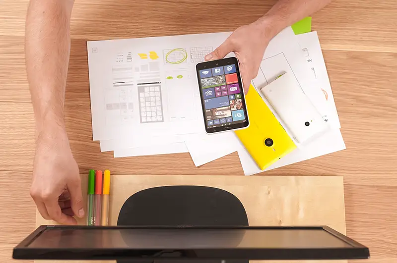 A person in front of desktop while holding smartphone