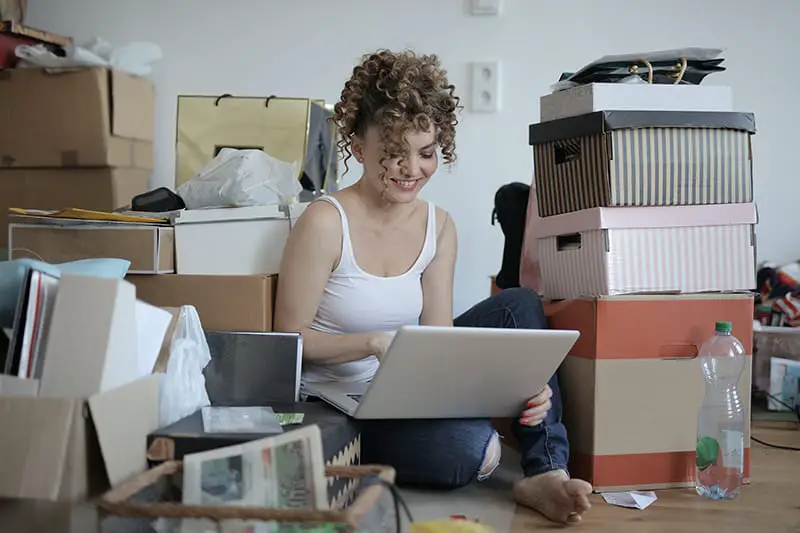 A woman with laptop shopping online in messy living room