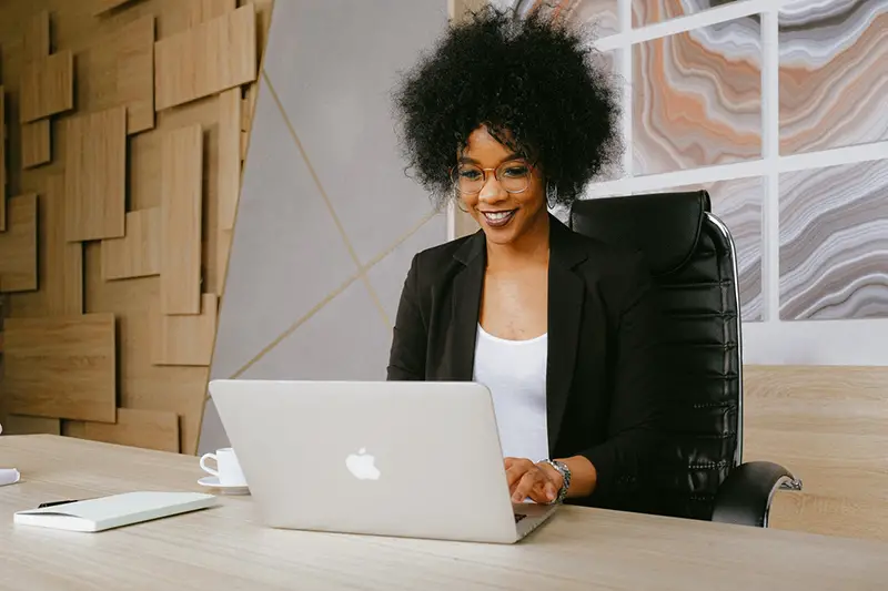 Woman in black blazer sitting at a desk using a Macbook