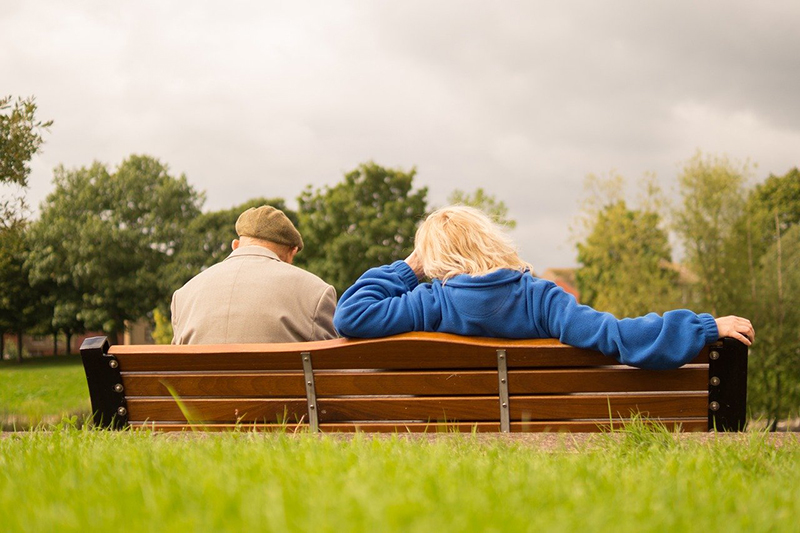 Man and woman sitting and resting on a bench in a park