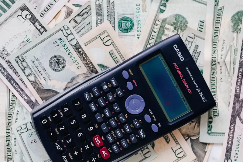 calculator placed over a stack of USA dollars