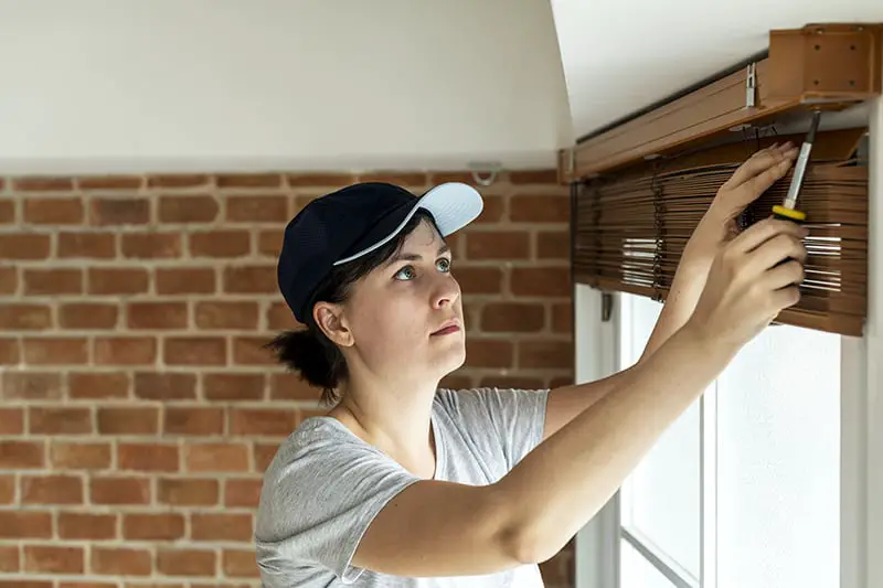 A woman installing window curtain