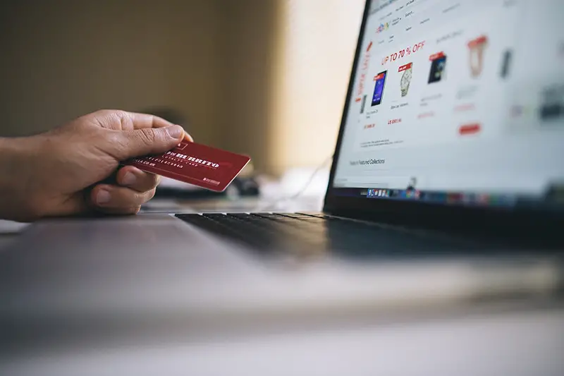 A person holding credit card in front of laptop screen