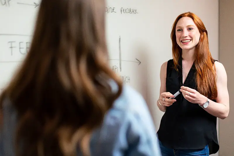 Two woman having a discussion about small business ideas on white board