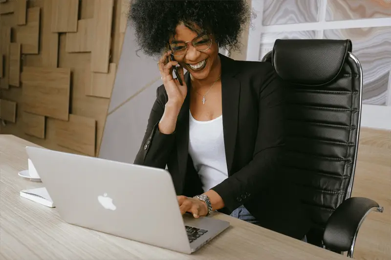 woman in black blazer sitting in office chair talking on the phone