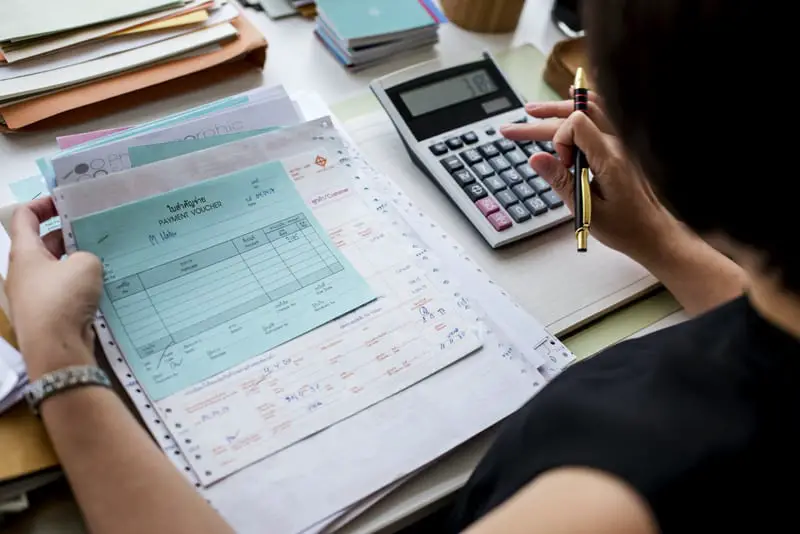 Women using calculator doing accounting and reviewing invoices.