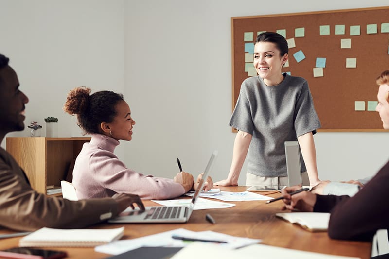 Woman wearing gray shirt standing in front of her colleagues