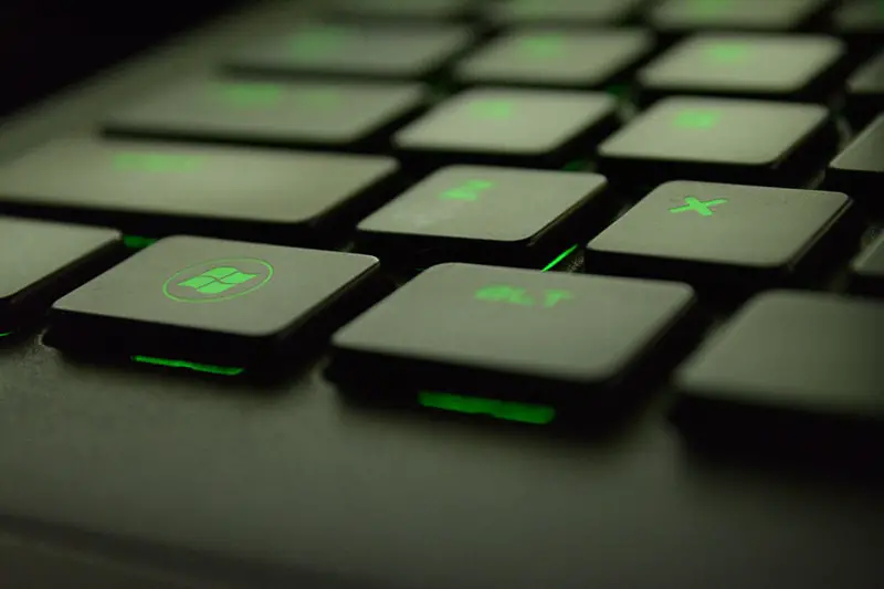 Close up of black keyboard with green back light. Focused on Microsoft window key