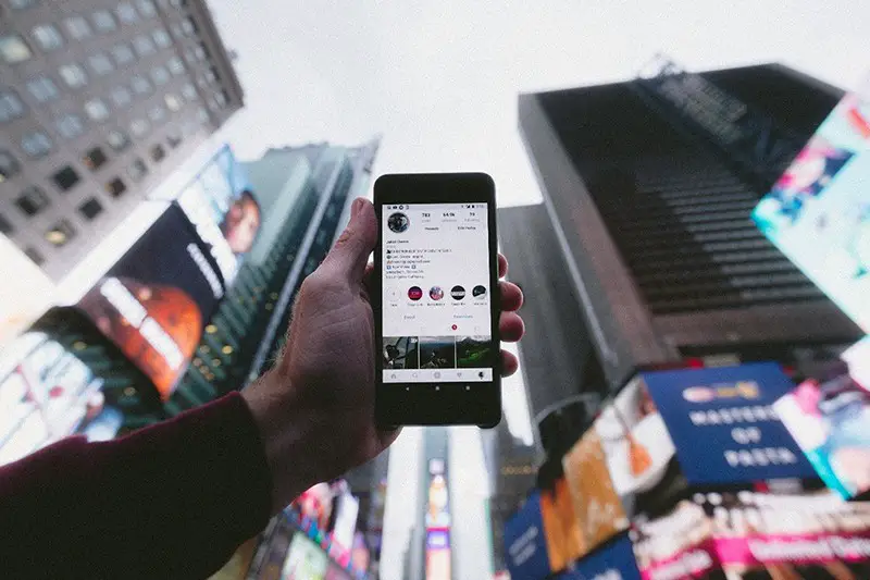 person outside point smartphone to the sky showing instagram story