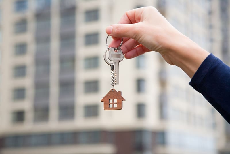 Person holding keys for real estate property on key ring with a little house