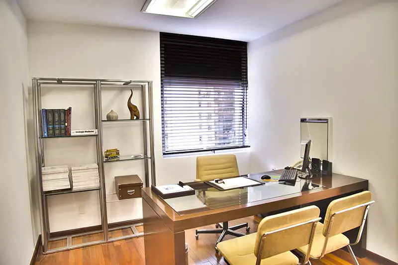 A small office with brown wooden desk