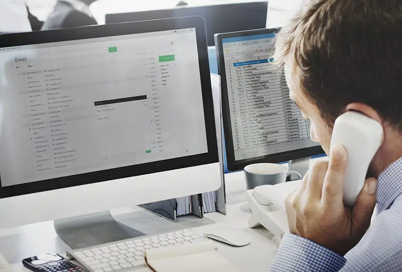 A man is writing an e-mail while on the phone