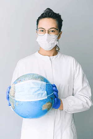 A nurse with eyeglasses wearing facemask while holding a globe