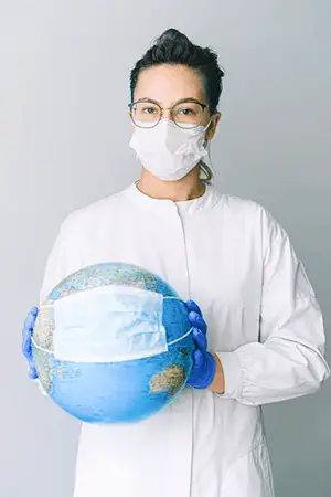 A nurse with eyeglasses wearing facemask while holding a globe