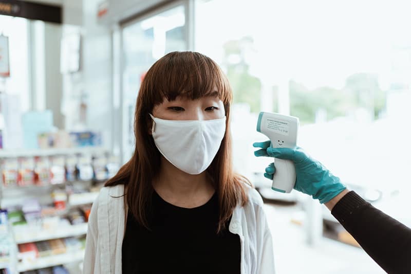 Woman wearing a face mask getting her temperature checked