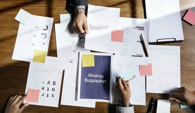 people around a table discussing marketing strategy and ideas – paperwork on the table