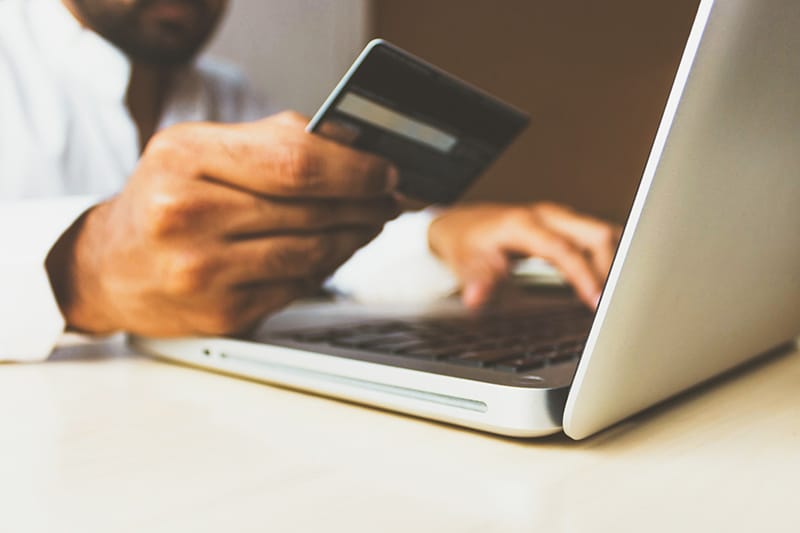 Man with a credit card using a laptop to make purchase from ecommerce business site