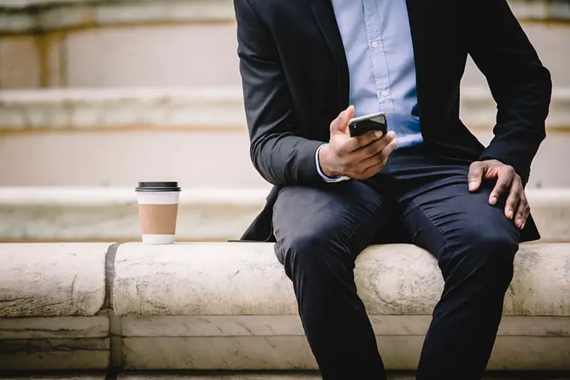 cropped image of businessman using smartphone while resting on a bench