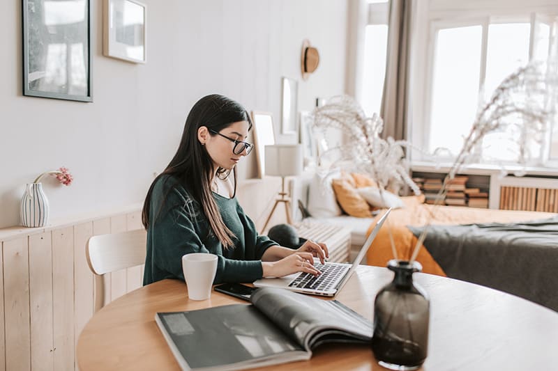 Female freelancer working on her laptop inside the bedroom