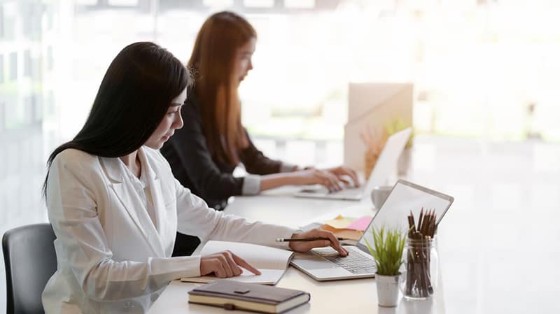 two women in a start-up business working at a desk on laptops