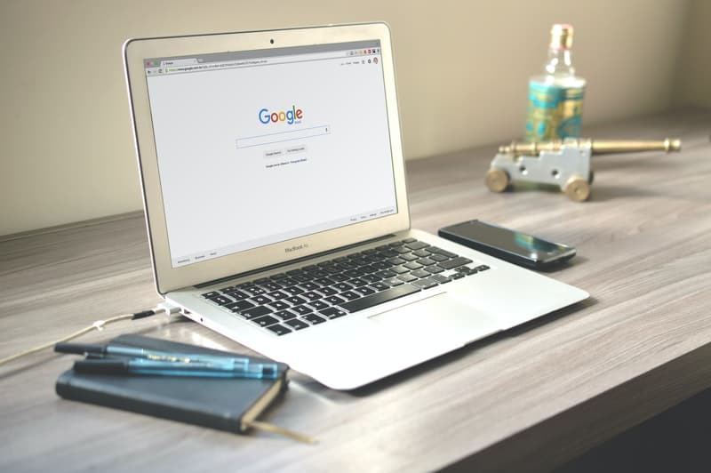 Macbook on desk next to smartphone and notebook