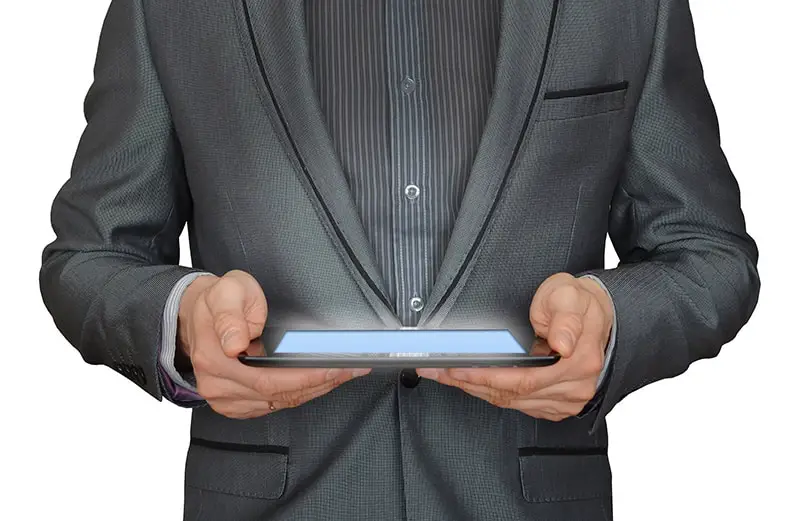A man in grey suit with tablet on hands