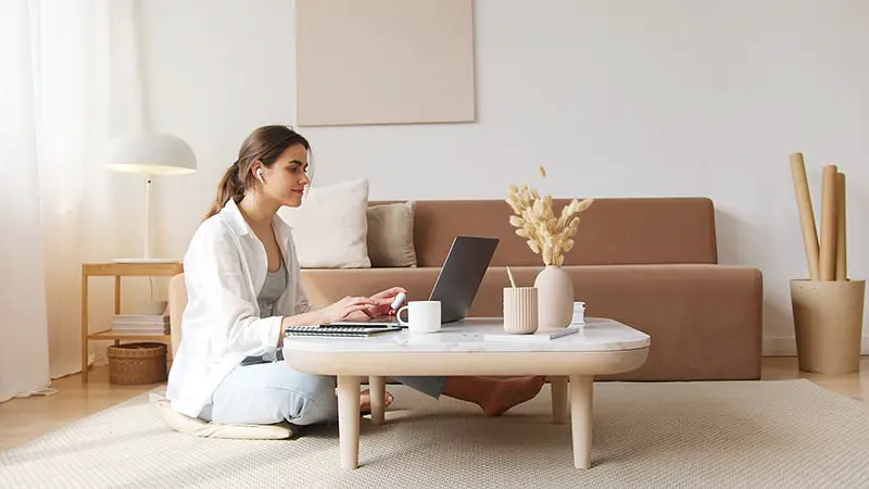 Woman working on her laptop while sitting on the floor