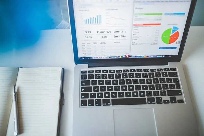 Laptop showing cash flow forecasts - graphs and charts – next to notebook 