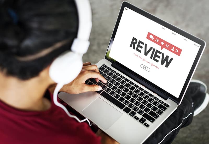 Person wearing headphones and looking at online review on laptop
