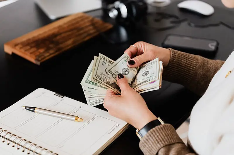 Woman on her desk counting dollars on her hand