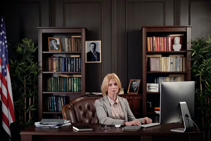 business lawyer in office sitting at desk next to US flag