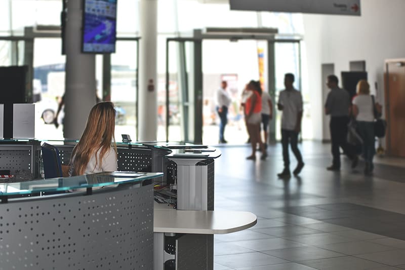 Receptionist sitting at desk in workplace reception area with sliding doors