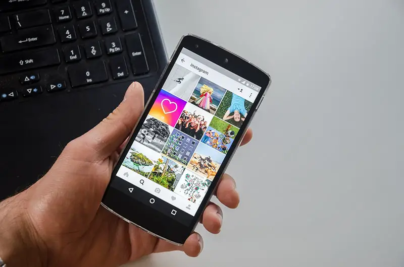 Person holding black smartphone with instagram apps on the screen