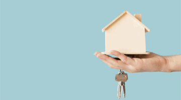 A toy house and a key on hand by a person