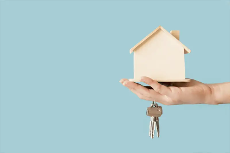 A toy house and a key on hand by a person