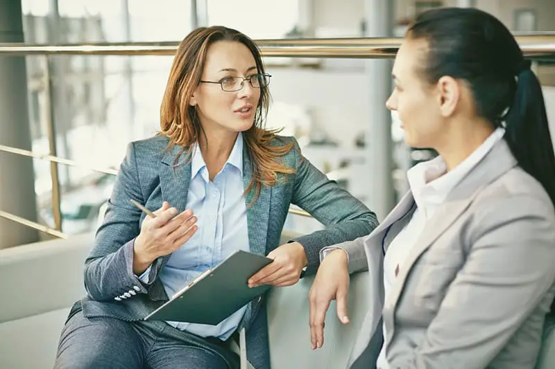 Two women sitting in the couch while talking