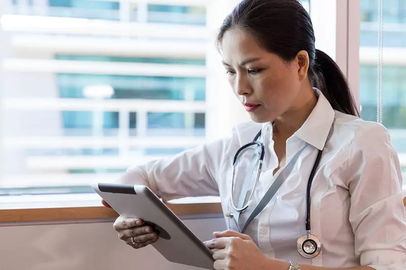 Female hospital worker looking at tablet computer