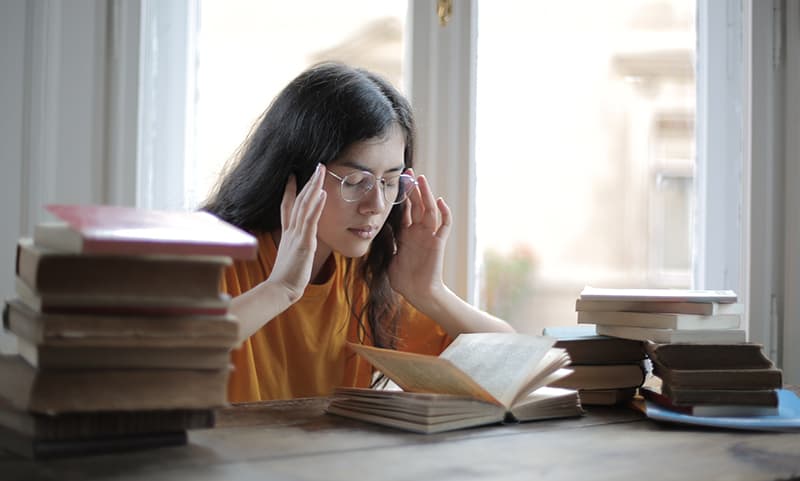 Female student suffering headache in the library