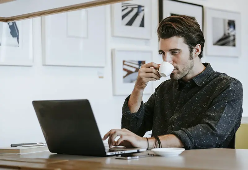 Man sipping a coffee while working