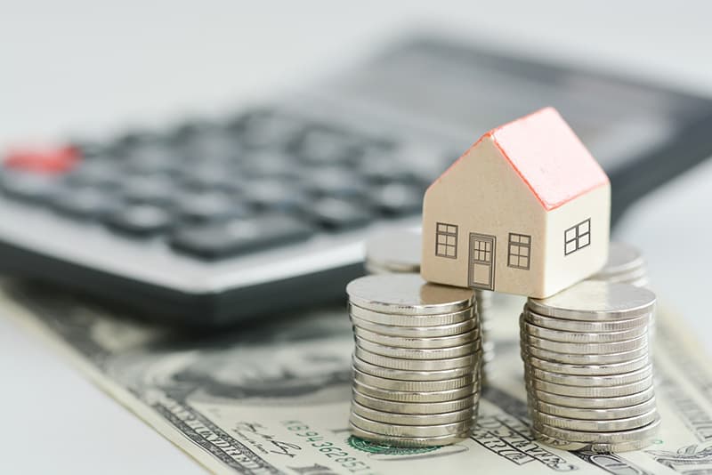 A wooden toy house on the top of money