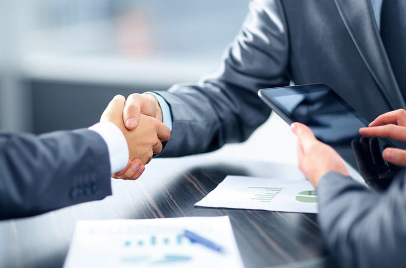 Two person wearing business suits doing the handshake