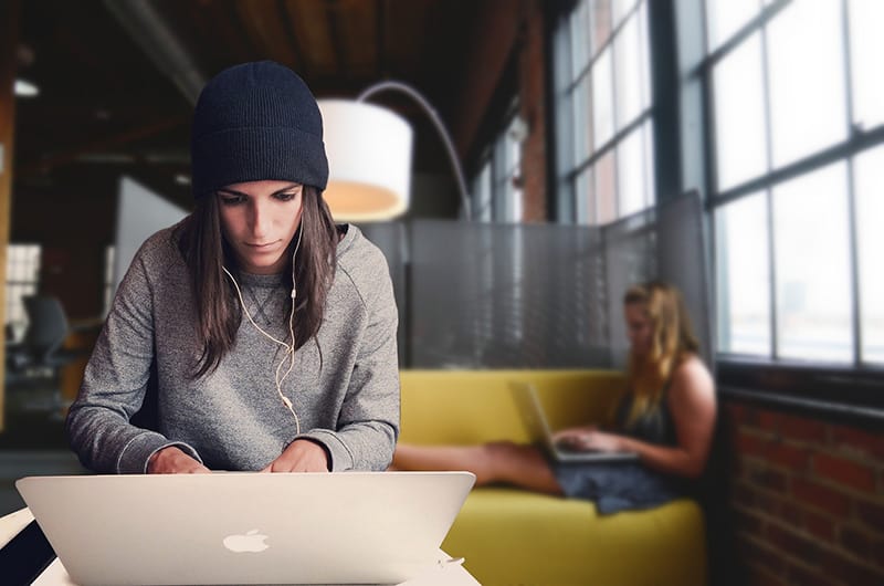 Woman in gray long sleeves working in front of her laptop