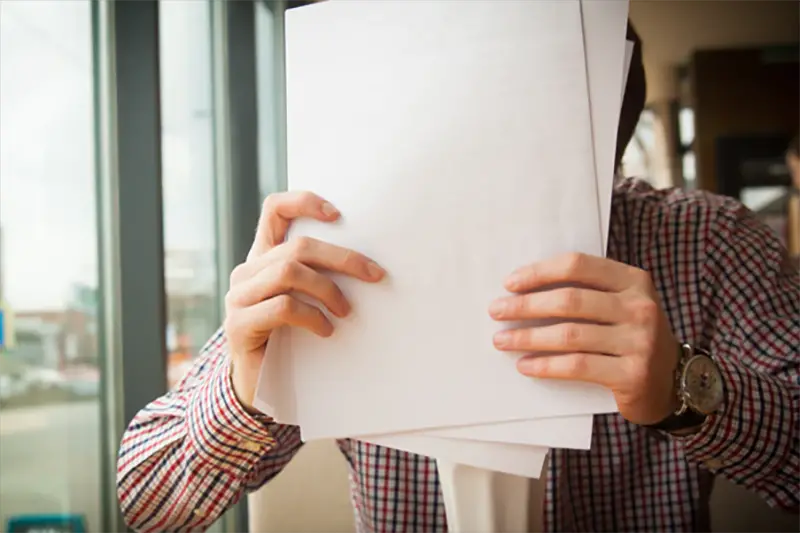 Person in checked shirt holding paper resume